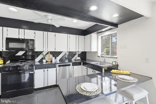 a kitchen with stainless steel appliances a stove a sink a microwave a dining table and chairs