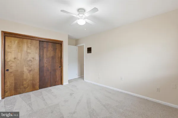 an empty room with a chandelier fan and closet