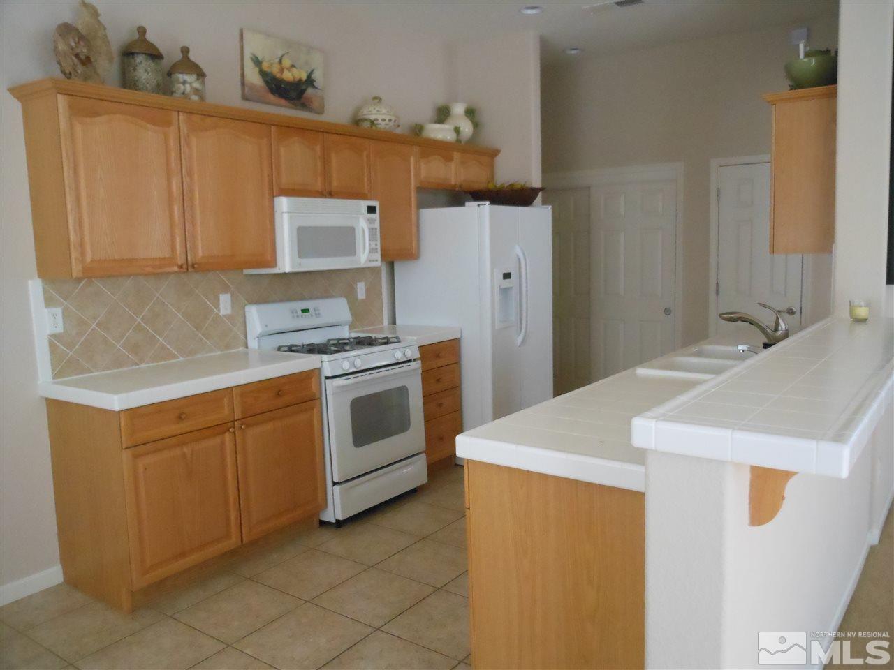 1624 Sewell Drive Reno, NV 89521 - Photo 3 of 14 a kitchen with granite countertop cabinets sink and white appliances