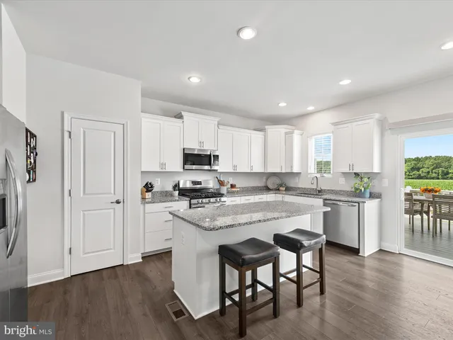 a kitchen with a sink a stove a refrigerator and white cabinets with wooden floor