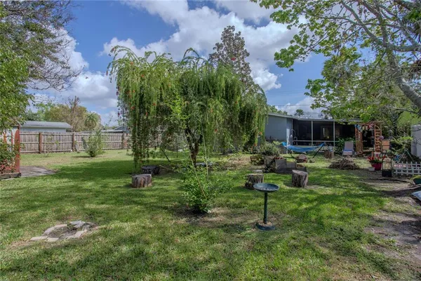 a view of a backyard with table and chairs potted plants and large tree