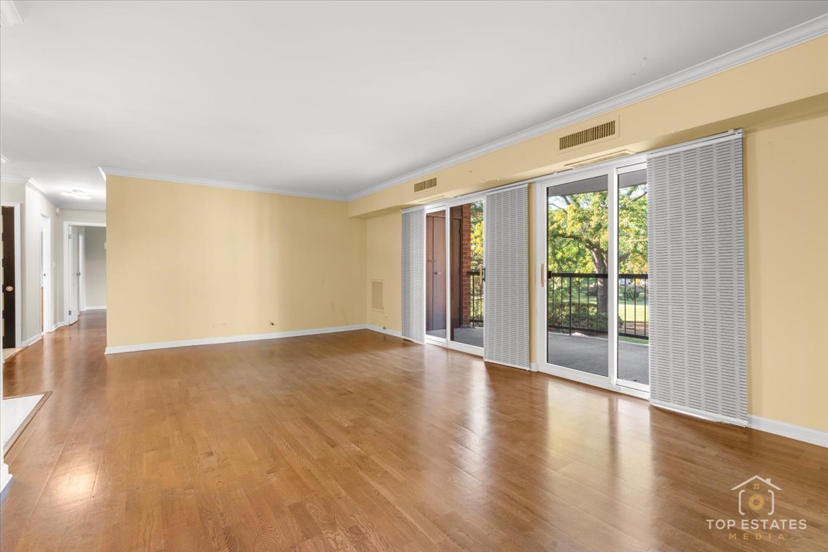 1615 East Central Road, Unit 218C Arlington Heights, IL 60005 - Photo 9 of 33 a view of an empty room with wooden floor and a window