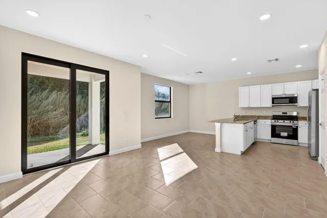 a view of kitchen with stainless steel appliances granite countertop a stove a sink and a microwave with granite countertops
