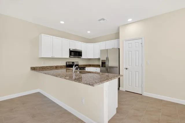 a kitchen with stainless steel appliances granite countertop a sink a stove a refrigerator a microwave a sink and cabinets