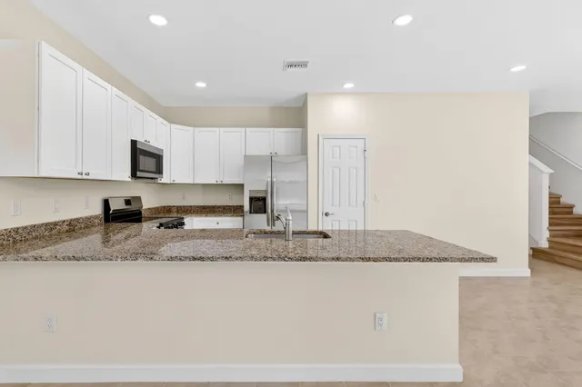 a kitchen with stainless steel appliances granite countertop a sink a stove a microwave and a refrigerator