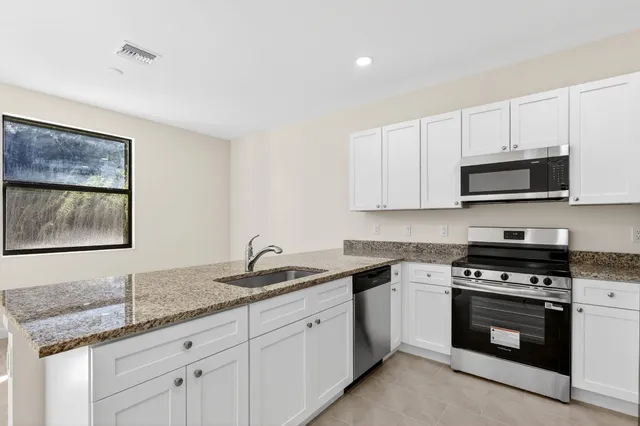 a kitchen with granite countertop white cabinets white stainless steel appliances and a sink