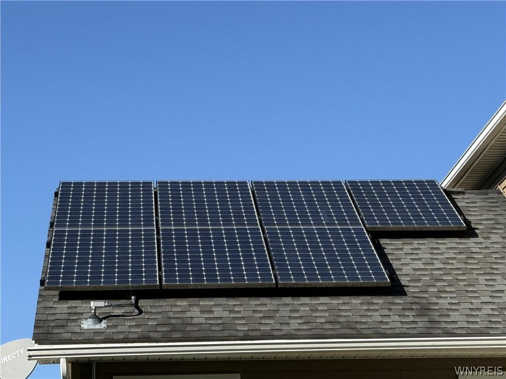 73 Chestnut Lancaster, NY 14086 - Photo 40 of 41 An energy-efficient rooftop features integrated solar panels set against a clear blue sky.