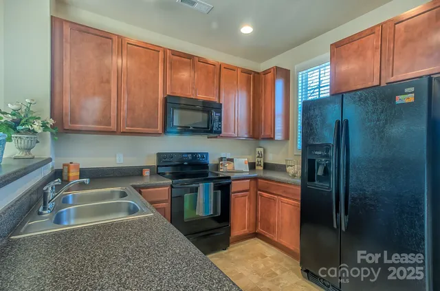 a kitchen with stainless steel appliances granite countertop a refrigerator a sink a stove a washer dryer and a dining table