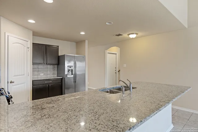 a view of a kitchen island a sink wooden floor and a refrigerator