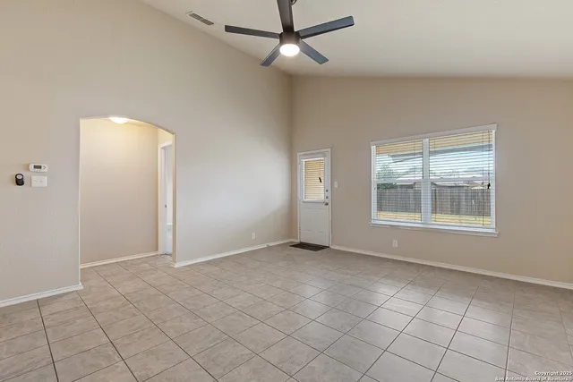 an empty room with windows and fan