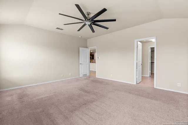 an empty room with ceiling fan and windows