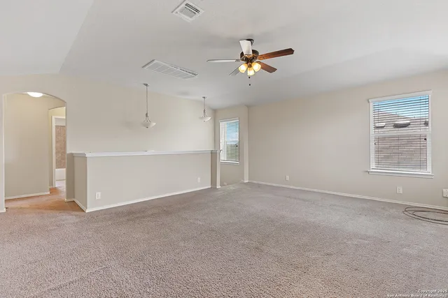 a view of an empty room with a ceiling fan and window