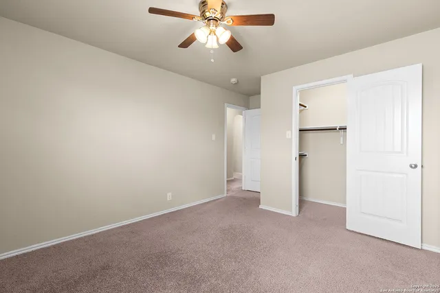 an empty room with closet and a chandelier fan