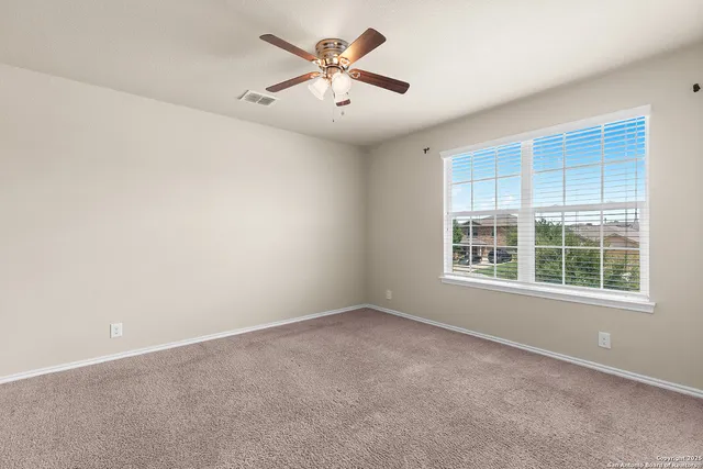 an empty room with a window and a fan
