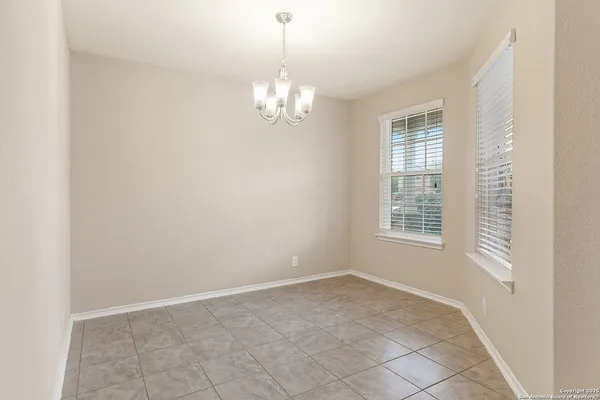 an empty room with chandelier fan and windows