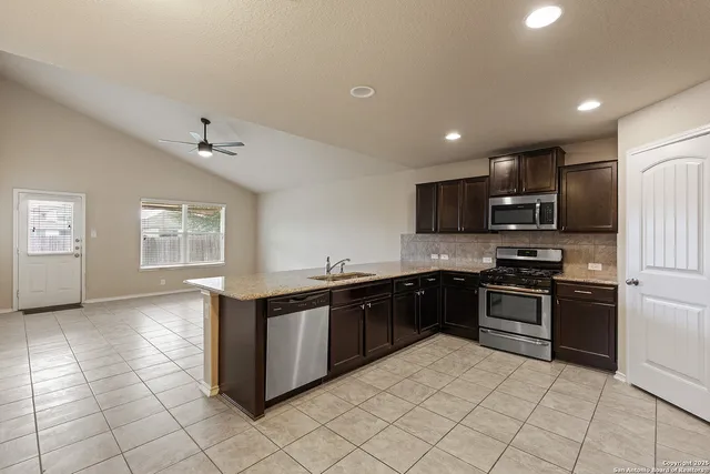 a large kitchen with stainless steel appliances granite countertop a stove and a sink