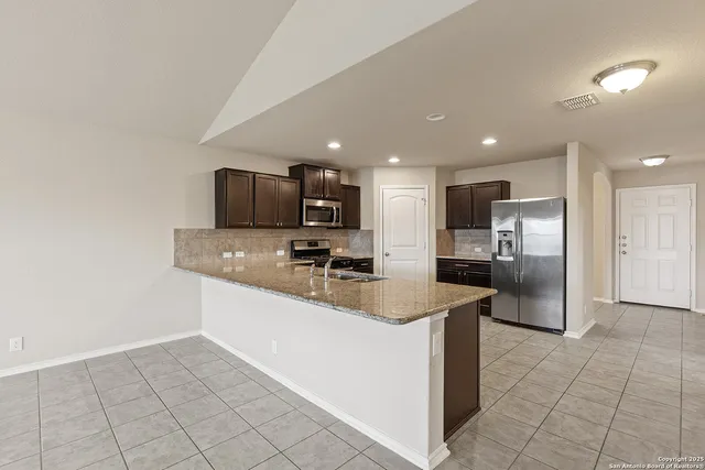 a kitchen with stainless steel appliances granite countertop a sink refrigerator and microwave