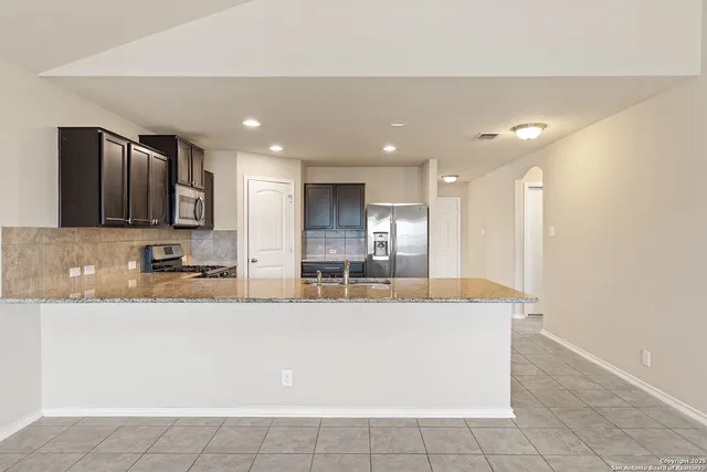 a large kitchen with granite countertop a large counter top stainless steel appliances and cabinets