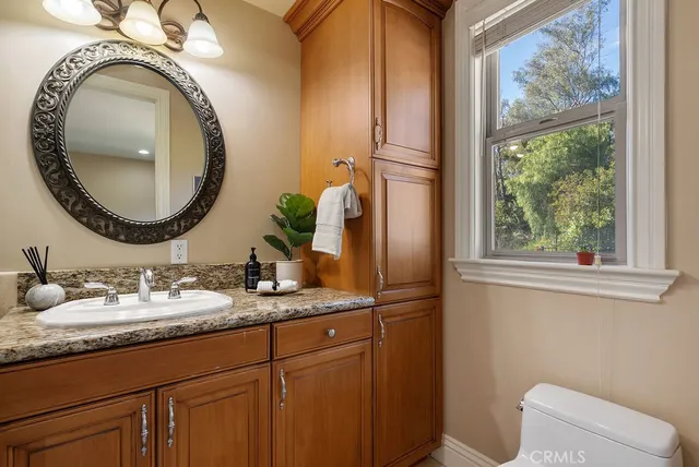 a bathroom with a granite countertop toilet a sink and a mirror
