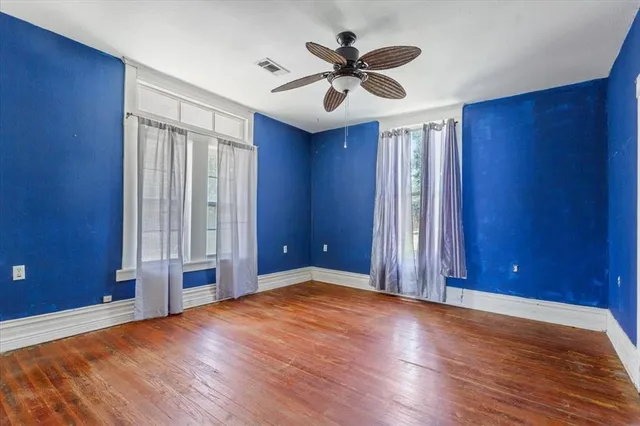 an empty room with wooden floor and windows