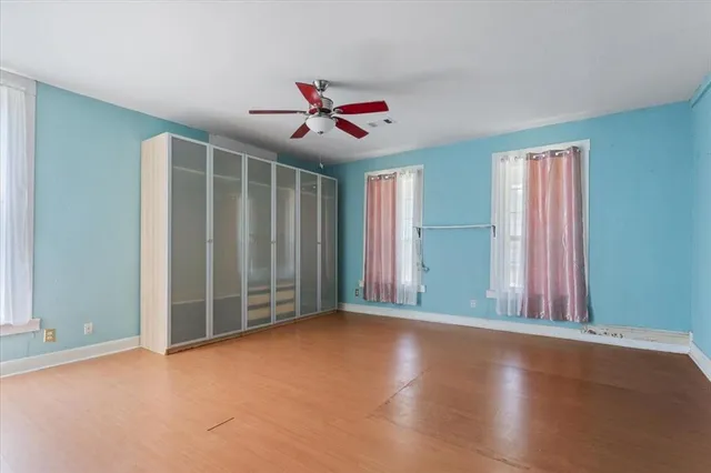 an empty room with windows and fan