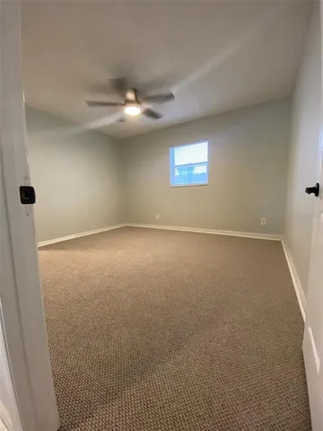 an empty room with a ceiling fan and a window