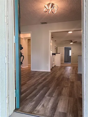 a view of a hallway with wooden floor and a bathroom