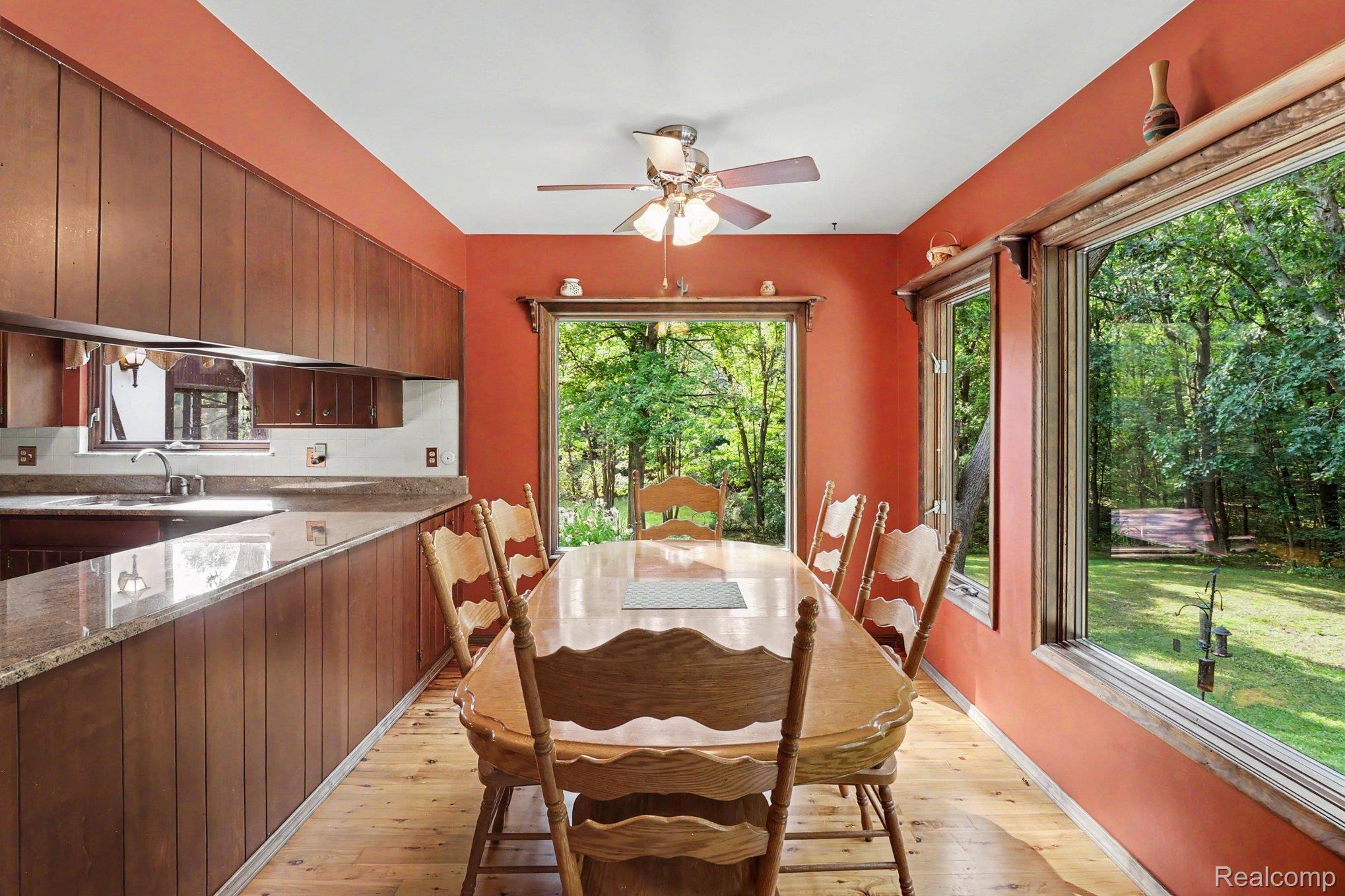 6300 North Raddatz Road Fowlerville, MI 48836 - Photo 14 of 42 Expansive windows, wood-finish flooring, wood-paneled walls, built-in cabinetry, and a ceiling fan