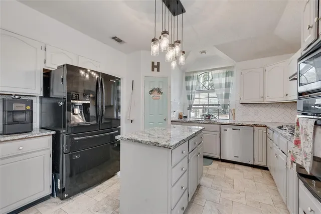 a kitchen with stainless steel appliances granite countertop a stove refrigerator and couches with kitchen view