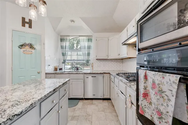 a kitchen with granite countertop a sink stainless steel appliances and chandelier