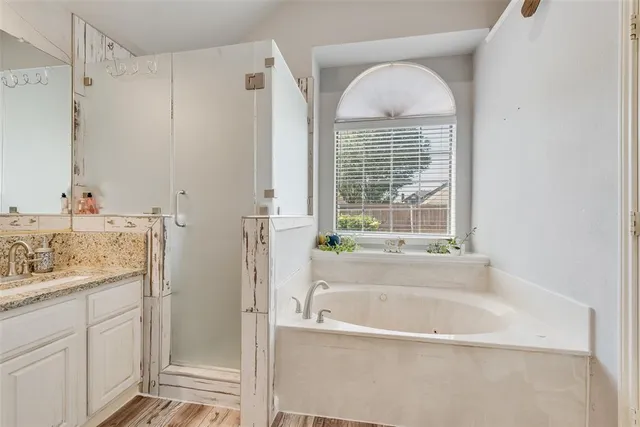 a bathroom with a tub a sink and a large mirror