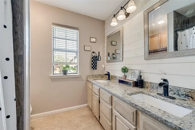 a bathroom with a granite countertop tub sink and mirror