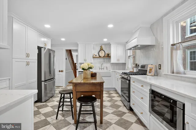 a kitchen with stainless steel appliances a dining table chairs and refrigerator