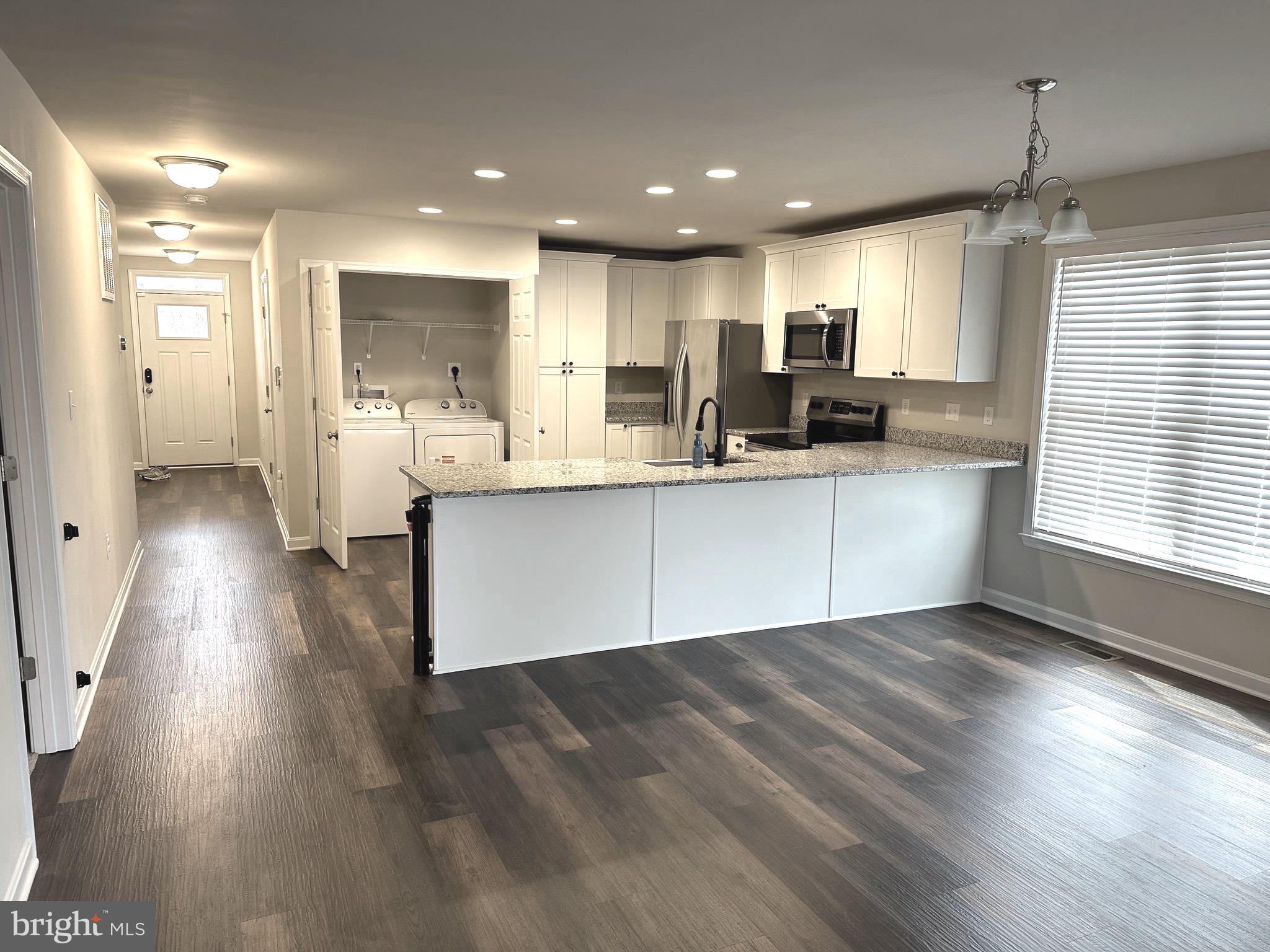 275 Nicholson Drive Colonial Beach, VA 22443 - Photo 3 of 22 a large white kitchen with wooden floors and stainless steel appliances