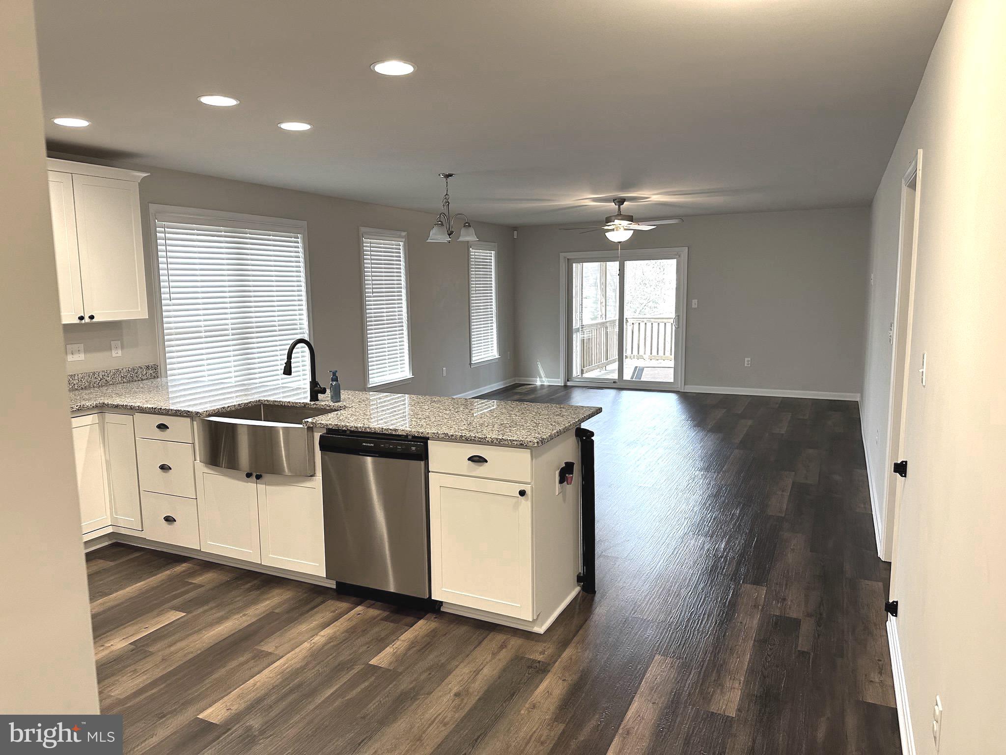 275 Nicholson Drive Colonial Beach, VA 22443 - Photo 6 of 22 a kitchen with stainless steel appliances kitchen island granite countertop a stove a sink and white cabinets with wooden floor