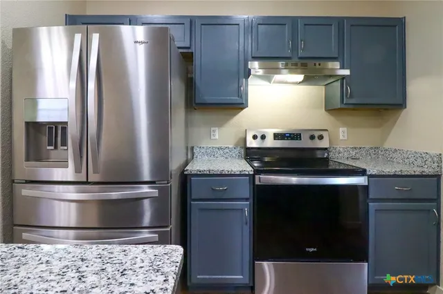 a kitchen with stainless steel appliances granite countertop a refrigerator and a stove