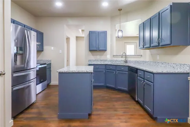 a kitchen with stainless steel appliances granite countertop wooden cabinets a refrigerator and a sink