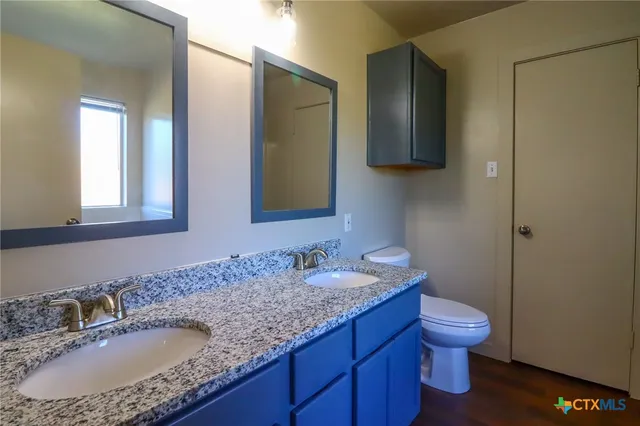 a bathroom with a granite countertop sink toilet and mirror