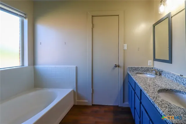 a bathroom with a granite countertop tub sink and mirror