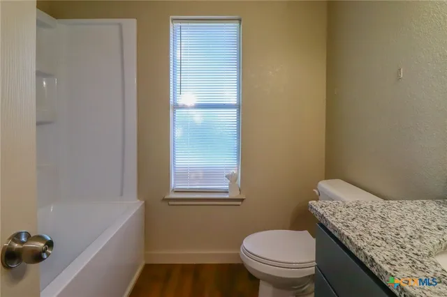 a bathroom with a granite countertop toilet and a sink