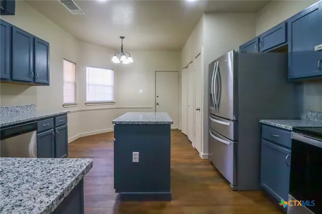 a kitchen with kitchen island granite countertop wooden cabinets and stainless steel appliances