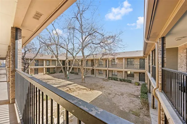 a view of a brick house with a wooden bench next to a road
