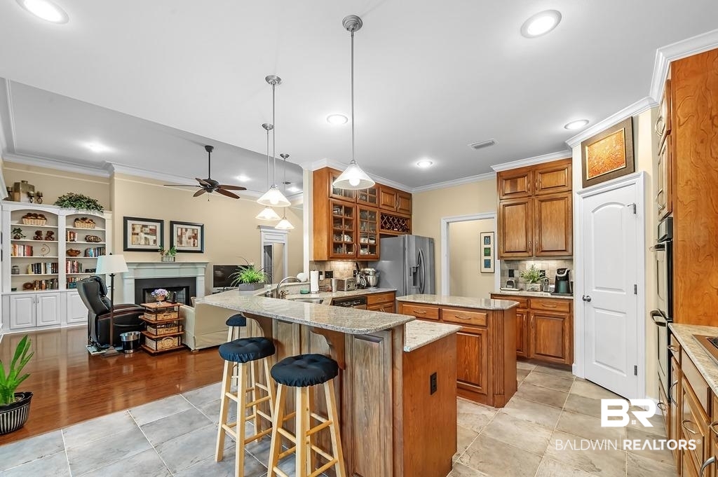 29976 Dolive Ridge Daphne, AL 36527 - Photo 22 of 58 Kitchen featuring a breakfast bar, backsplash, light wood-type flooring, stainless steel fridge with ice dispenser, and ceiling fan