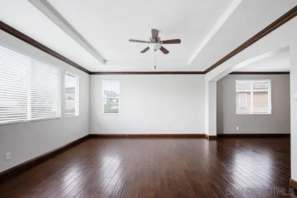 an empty room with wooden floor a ceiling fan and windows