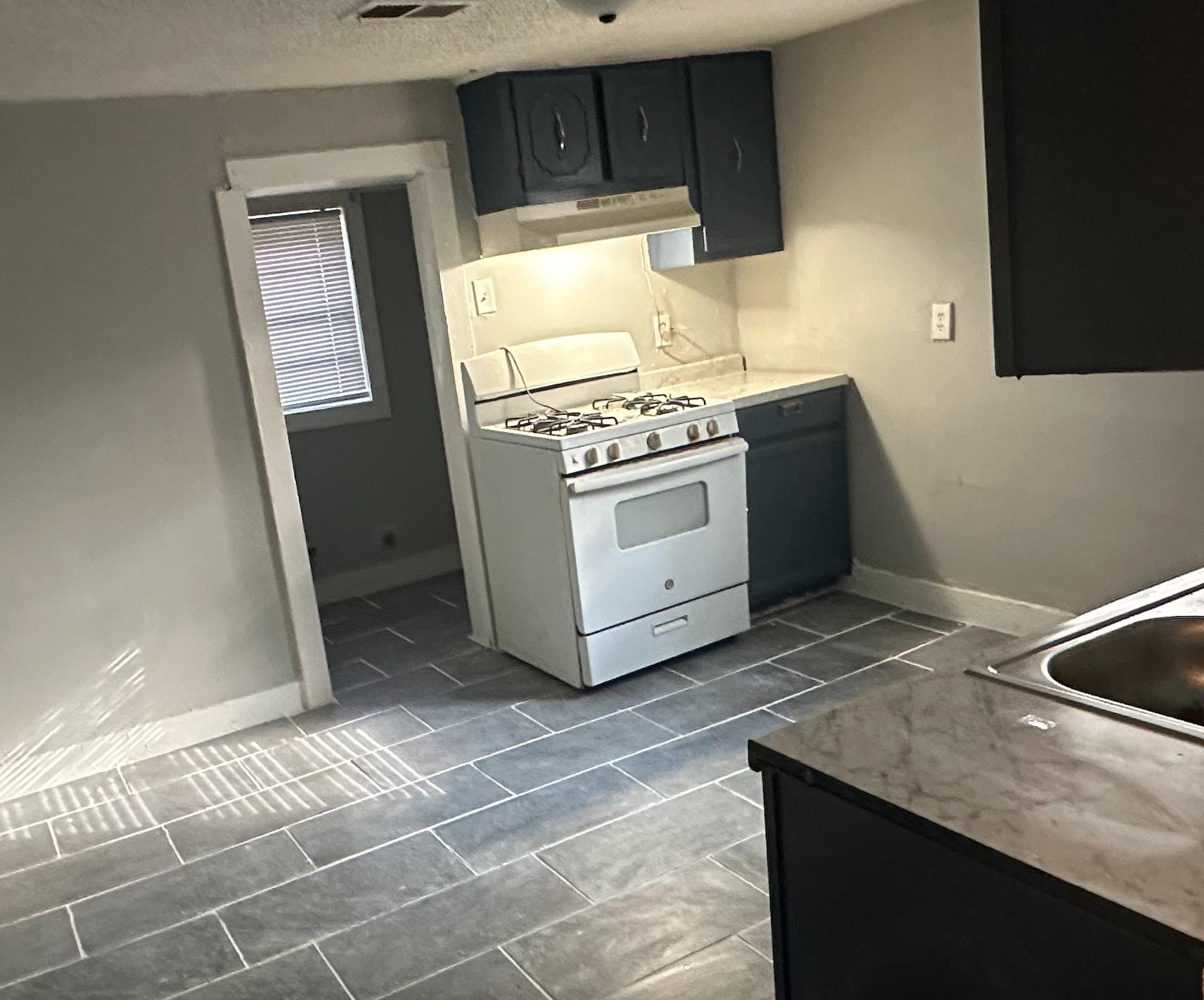 3579 Kendrick Road Memphis, TN 38108 - Photo 3 of 8 Kitchen with a textured ceiling, exhaust hood, white range with gas cooktop, and dark tile patterned flooring