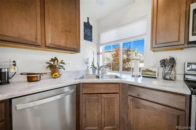 a kitchen with stainless steel appliances granite countertop a sink dishwasher a refrigerator and cabinets with wooden floor