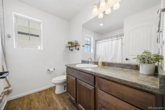 a bathroom with a granite countertop sink a toilet and mirror
