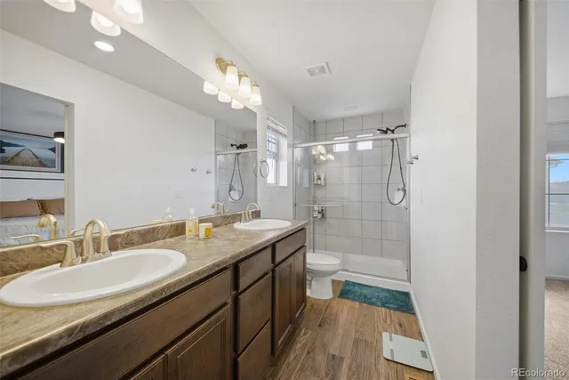 a bathroom with a granite countertop sink a toilet a mirror and shower