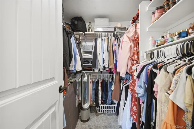 a view of walk in closet with clothes and shoes