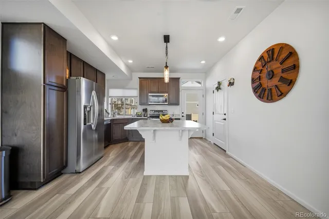 a kitchen with a refrigerator and a wooden floor